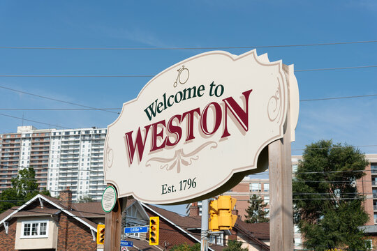 decorative welcome sign to historic Weston (Ontario, Canada) now part of the city of Toronto photographed against an urban view and blue sky
