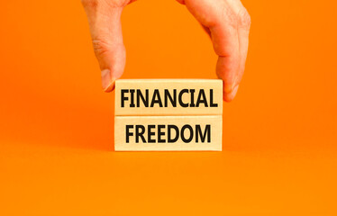 Financial freedom symbol. Concept words Financial freedom on beautiful wooden blocks. Beautiful orange table orange background. Businessman hand. Business financial freedom concept. Copy space.