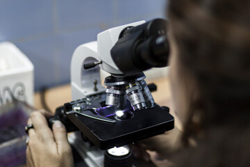 Scientist looking through microscope in laboratory