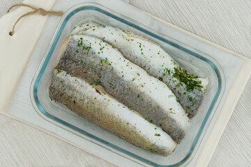Marinated hake on a ceramic board on white background. Ready to cooking. Hake Filet. Top view.