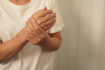 A woman uses her other hand to feel pain and tingling. along with Guillain-Barre syndrome and numbness in the hands Elderly woman tries to massage herself to relieve wrist pain - obrazy, fototapety, plakaty