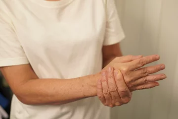Fotobehang A woman uses her other hand to feel pain and tingling. along with Guillain-Barre syndrome and numbness in the hands Elderly woman tries to massage herself to relieve wrist pain © kiattisak
