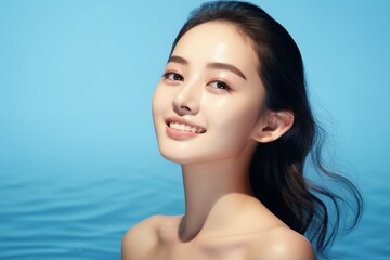 Beautiful asian woman smile with clean fresh skin on blue background. - obrazy, fototapety, plakaty
