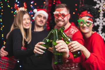 Four friends celebrating New year toasting with beer bottles. Focus on bottles