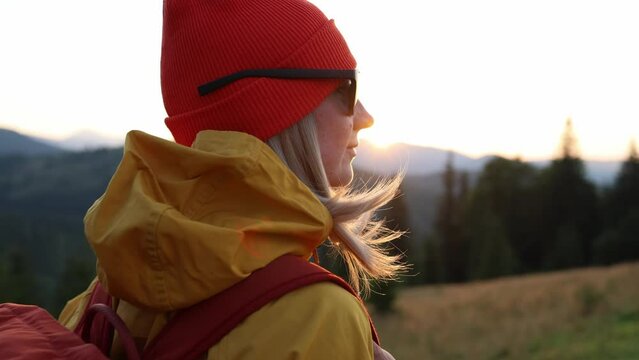 Woman hiker portrait, hiking backpacker traveler at sunset time. Beautiful mountain landscape view. Hiking, backpacking. 4K slow motion video