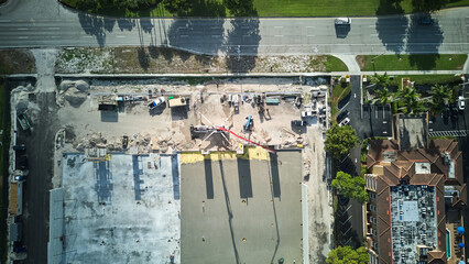 Aerial wide photo of residential and commercial construction site, concrete truck mixers dump cement mixture to pour floor 