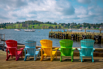 Multicolour Adirondack chairs facing bay, Lunenburg harbour, Nova Scotia, Canada. Photo taken in September 2023.