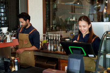 Businessman, cafe owner, Asian woman and men of different ethnicities. Making coffee orders customers order through ordering machine. young woman taking orders from customers cute smile. small cafe