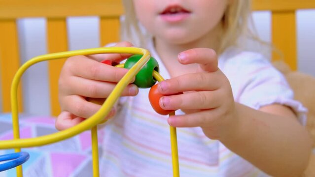 Litle cute child, girl plays with colored wooden educational labyrinth for kids, development of fine motor skills, concept of development of creativity, play activity at home and in kindergarten