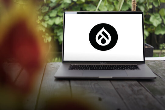 Drupal logo, a free and open-source web content management system (CMS) written in PHP, displayed on a MacBook Pro screen