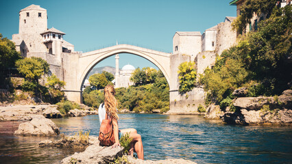Female tourist looking at famous old bridge and river of Mostar- tour tourism,travel,vacation in Bosnia - obrazy, fototapety, plakaty