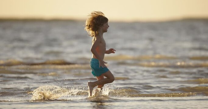 Happy smiling kid 5-7 years old running along beach in water slow motion. Concept of happy childhood, safe, carefree feeling of inspiration fulfillment. Close to family, safe experience of emotions