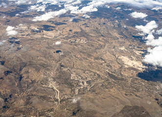 View from 10,000 meters (33,000 feet) of the mountains and arid landscape of western Peru. Dry river paths, dense clouds and no vegetation. - obrazy, fototapety, plakaty