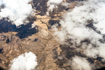 View from 10,000 meters (33,000 feet) of the mountains and arid landscape of western Peru. Dry river paths, dense clouds and no vegetation. - obrazy, fototapety, plakaty