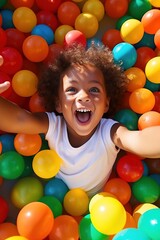  laughing child boy having fun in ball pit on birthday party in kids amusement park and indoor play...