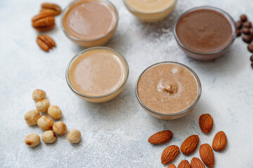 Homemade nuts butter in a glass jars with various nuts.