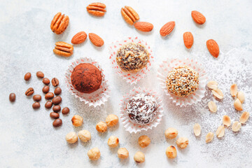 Fototapeta na wymiar Superfood, raw healthy vegetarian snack, Medjool dates covered by chocolate, and various energy balls with nuts.