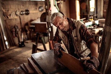 Senior male carpenter measuring wood in a carpentry shop