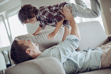 Young father playing and having fun with his son on the couch at home