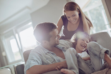 Young family bonding and having fun on the couch at home