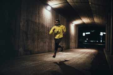 Young man sprinting under a bridge in the city