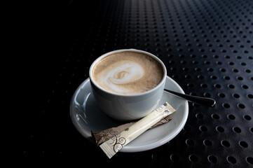 A cup of coffee on a black table.  Isolate.