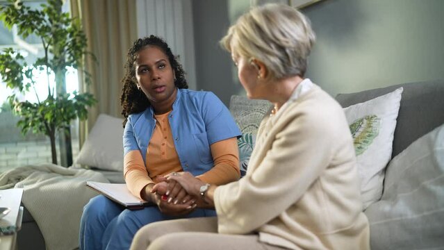 Senior woman consulting her caregiver on the couch at home