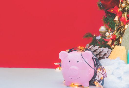 piggy bank decorated in Christmas celebration theme on white table reb background with copy-space, family spent time together in winter Christmas holiday