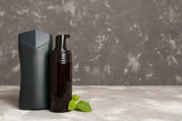 Men cosmetic bottles with mint leaves on concrete background