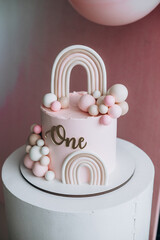 a beautiful pink cake with balls stands on a white stand with the inscription one river