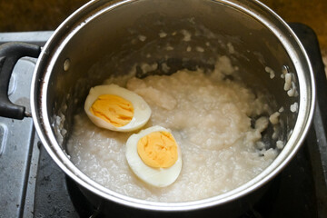 rice porridge and boiled eggs in an open pan as a baby's breakfast menu.