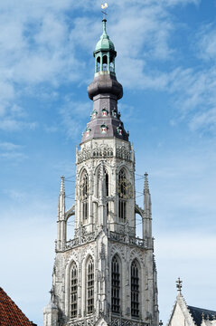 the gothic church tower of the protestant onze-Lieve-Vrouwekerk in breda against a blue sky with clouds