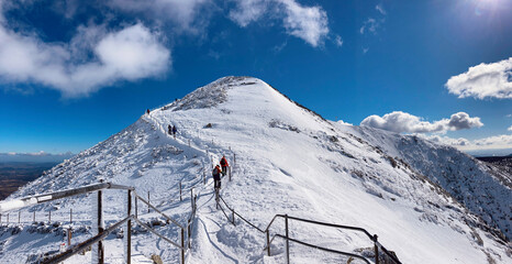 Hikers summiting the Sněžka peak in Krkonoše mountains, Czech Republic. Winter high altitude...