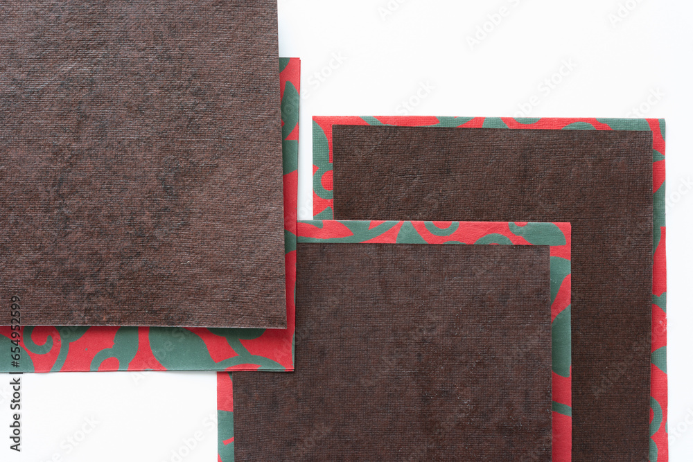 Wall mural brown paper pieces on top of red paper with green pattern