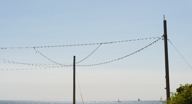 cord lighting and lake with sail boats - Powered by Adobe