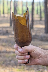 the hand of an aggressive criminal holds a piece of glass brown sharp broken bottle on the street