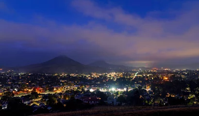 Fototapeten Schwarz hazy morning with city lights, mountain, sky  © Mark