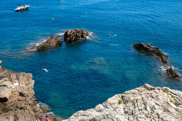 Image of the Mediterranean Sea from the Costa Brava, with tourists swimming in its crystal-clear waters.