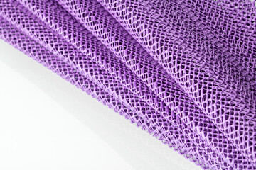 A lavender-colored synthetic kitchen napkin is folded into folds like a fan on a white background