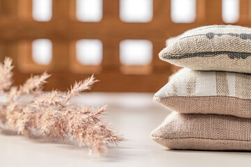 Domestic life. A stack of three pillows, a dry plant stem on a background of a wooden lattice