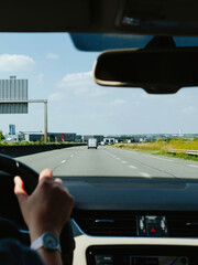 On a French freeway, a female driver exhibits adept control over her car with her hand firmly...