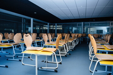 An empty school canteen showcases chairs lifted onto tables, emphasizing the room's cleanliness...