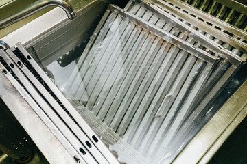 Heavy-duty sink containing multiple filters from industrial-grade hoods, immersed in a solution specifically designed for deep cleaning and degreasing