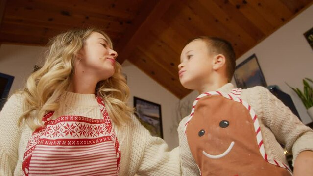 Low angle RED camera shot of little helper son kid kissing beautiful mother having fun at home kitchen. Happy family loving mother hugging her little boy child. Family love bonding trust concept 4K