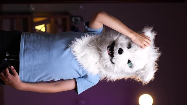 vertical video boy in a wolf mask is thoughtful scratches his head, gesture 