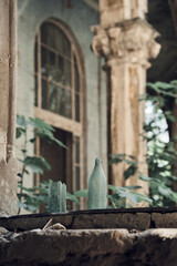 Broken bottles stand on the windowsills. Column with order and vintage window in the background. Abandoned soviet spa resort (sanatorium) Metallurg, in Tskaltubo, Georgia. 