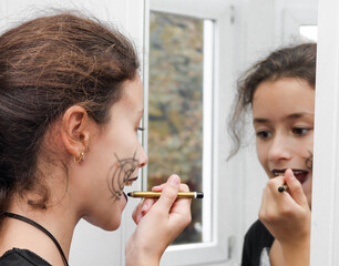 Caucasian teenage girl doing makeup for Halloween.