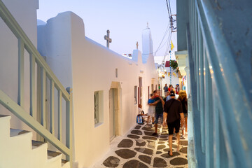 Unknown people coming and going on a narrow street in Mykonos - obrazy, fototapety, plakaty