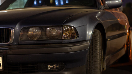 Fototapeta premium Front headlight of an old European car in the evening city