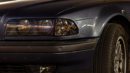 Front headlight of an old European car in the evening city